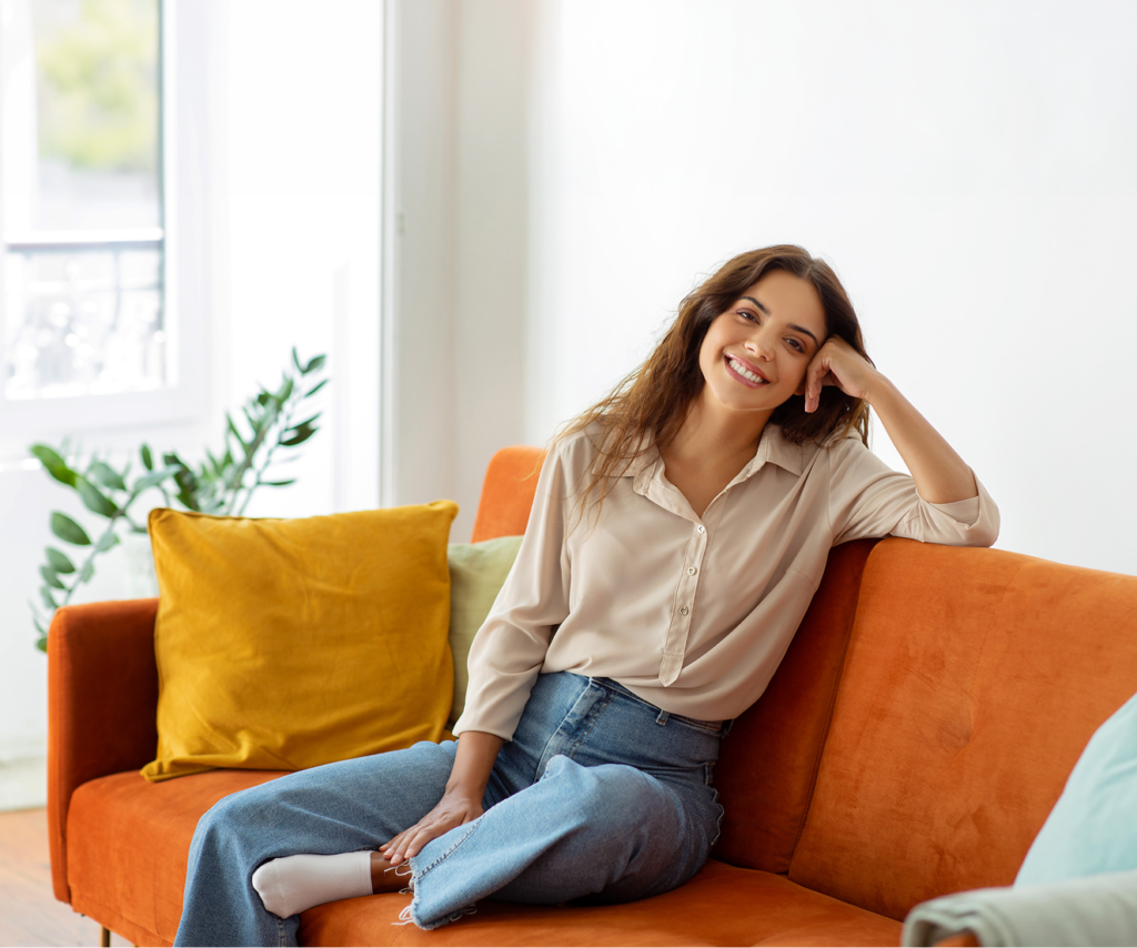 Frau auf oragenem Sofa lächelnd